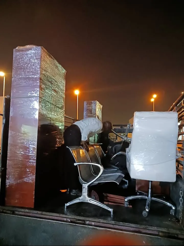 دولاب مغلف وكراسي مكتب محملة على شاحنة ليلًا