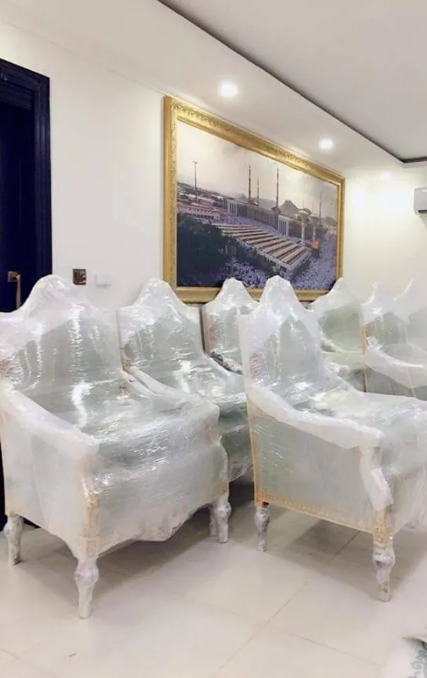 كراسي كلاسيكية بيضاء مغلفة بالنايلون الشفاف في صالة