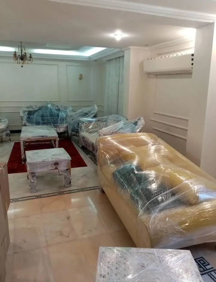 كنب مغلف بالنايلون الشفاف في صالة بسجادة حمراء